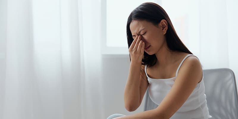 woman-sitting-down-with-pain-in-her-nose